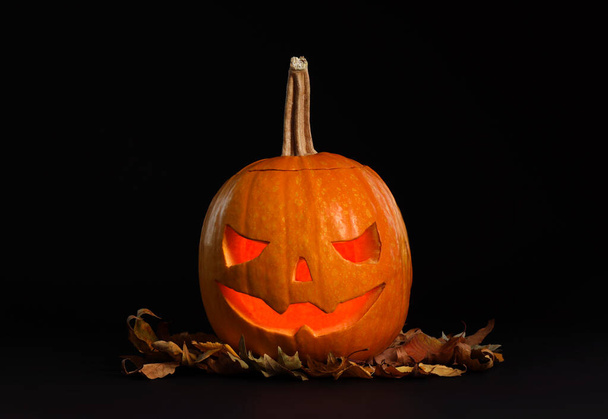 Pumpkin head with autumn leaves on black background. Jack lantern - traditional Halloween decor - Fotó, kép
