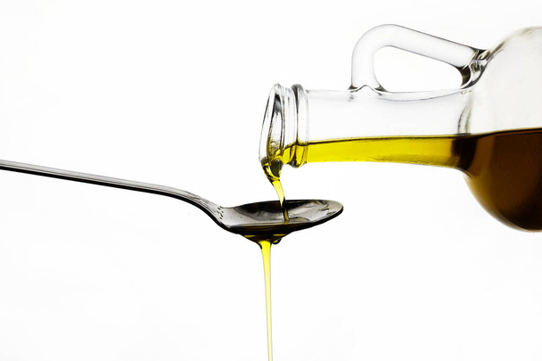 pouring olive oil from glass bottle on white background - Фото, зображення