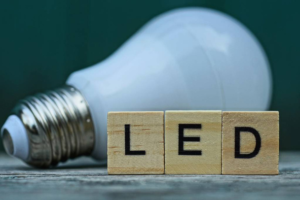 mot LED en lettres de bois et une ampoule blanche sur une table grise
 - Photo, image