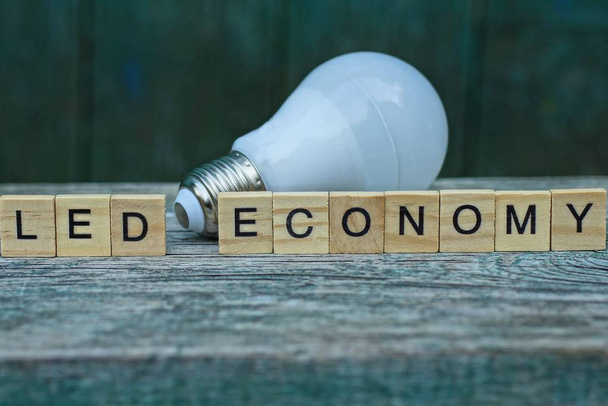 слово led економіка з дерев'яних літер і білої лампочки
 - Фото, зображення