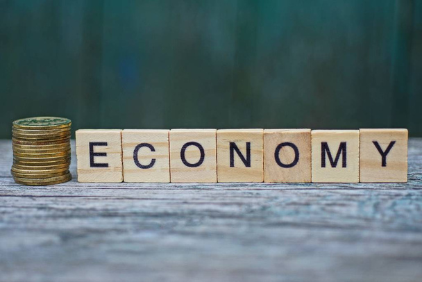 слово економіка з дерев'яних літер і монет на сірому столі
 - Фото, зображення