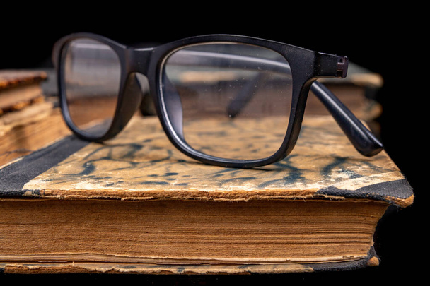 Old yellowed book and black glasses.  - Foto, imagen