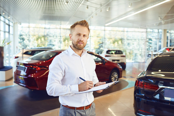A car dealer standing in a showroom. - Photo, Image