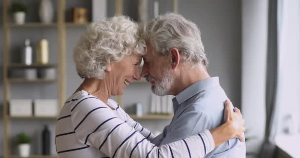 Affectionate elderly grandparents couple embracing bonding together at home - Metraje, vídeo