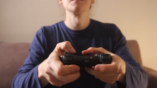 Closeup of man's hands playing video games on gaming console sitting on the couch - Materiaali, video