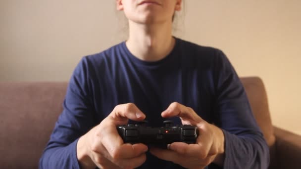 Closeup of man's hands playing video games on gaming console sitting on the couch - Πλάνα, βίντεο
