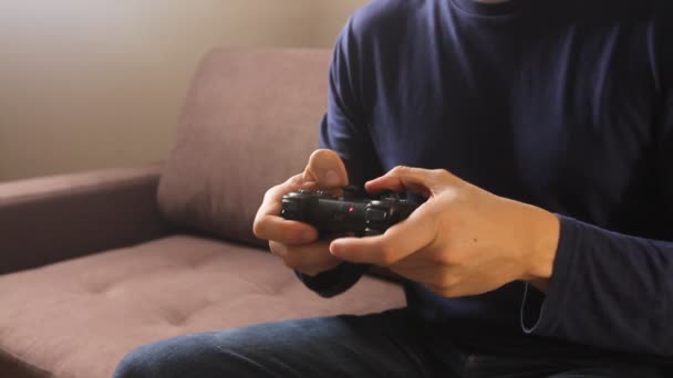 Closeup of man's hands playing video games on gaming console sitting on the couch - Filmati, video