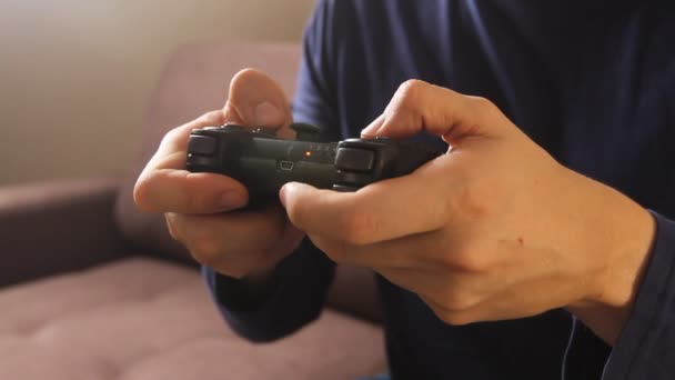 Closeup of man's hands playing video games on gaming console sitting on the couch - Video