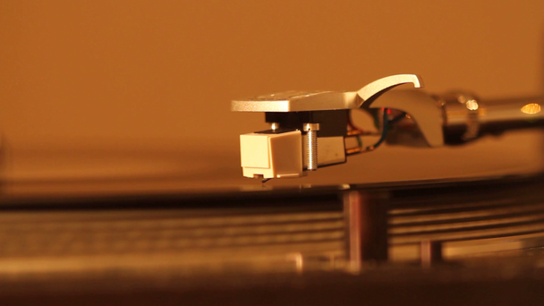Sluiten van draaitafel naald op een vinyl plaat. Draaitafel speelt vinyl. Naald op draaiend zwart vinyl. Achtergrondverlichting - Video