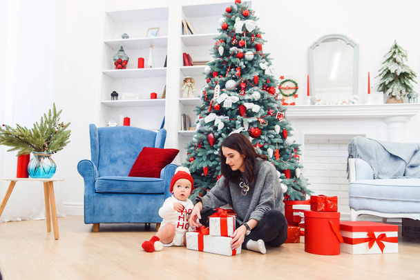 Charming toddler with her mother unpacking holidays gift. - Foto, Imagen