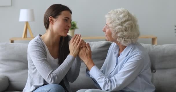 Caring young woman granddaughter holding old grandma hands talking bonding - Filmagem, Vídeo