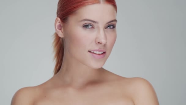 Studio portrait of young, beautiful and natural redhead woman applying skin care cream. Face lifting, cosmetics and make-up. - Metraje, vídeo