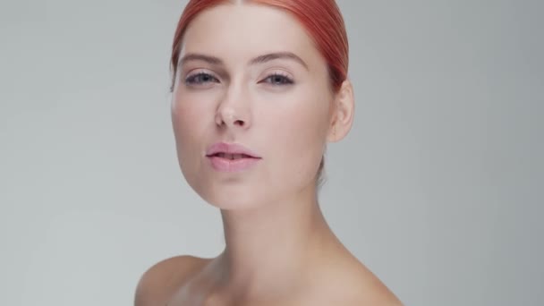 Studio portrait of young, beautiful and natural redhead woman applying skin care cream. Face lifting, cosmetics and make-up. - Кадри, відео