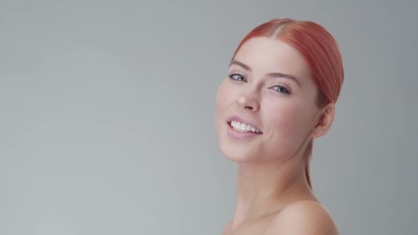 Studio portrait of young, beautiful and natural redhead woman applying skin care cream. Face lifting, cosmetics and make-up. - Materiał filmowy, wideo