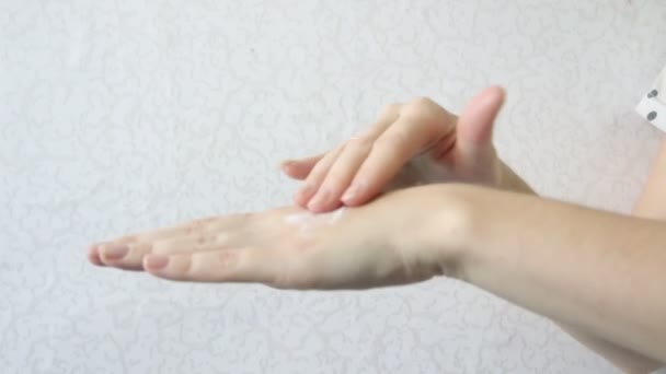 Rubbing cream into hands on a light background. Hand skin care. Female young hands. Apply cream. Moisturizing the hands. Healthy beautiful skin - Footage, Video