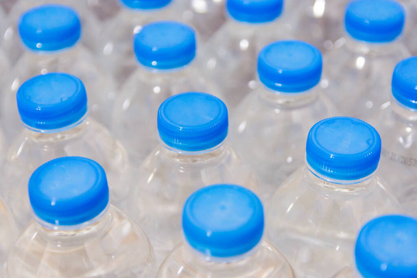 Řada lahví s vodou. Lahvičky s modrými uzávěry pro pitnou vodu - Fotografie, Obrázek