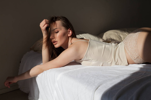 mooie vrouw in licht ondergoed in de slaapkamer op het bed - Foto, afbeelding