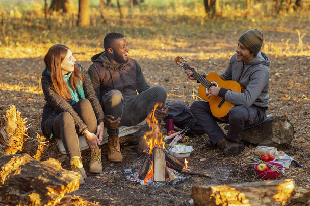 Grupo de pessoas acampar e cantar em florestas de outono
 - Foto, Imagem