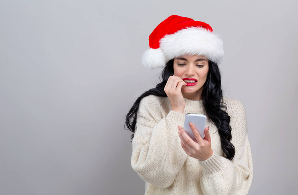 Young woman in a Santa hat using her smart phone - Foto, Bild
