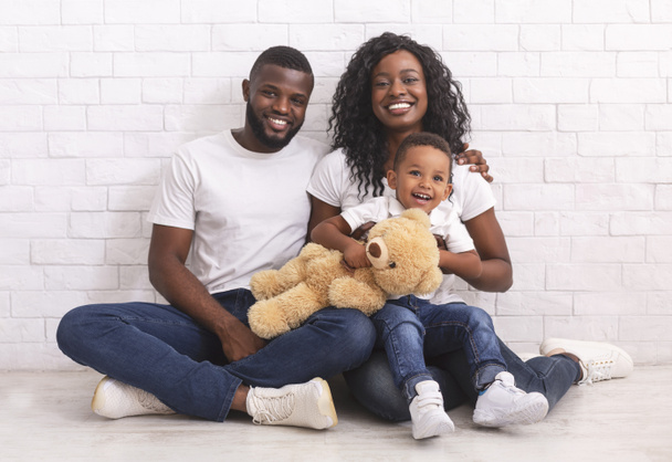 Heureuse famille noire avec petit fils assis sur le sol ensemble
 - Photo, image