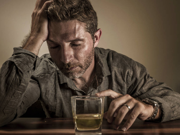 Attractive alcoholic man . depressed addict isolated in front of whiskey glass drunk and wasted in dramatic expression suffering alcoholism and alcohol addiction - Foto, immagini
