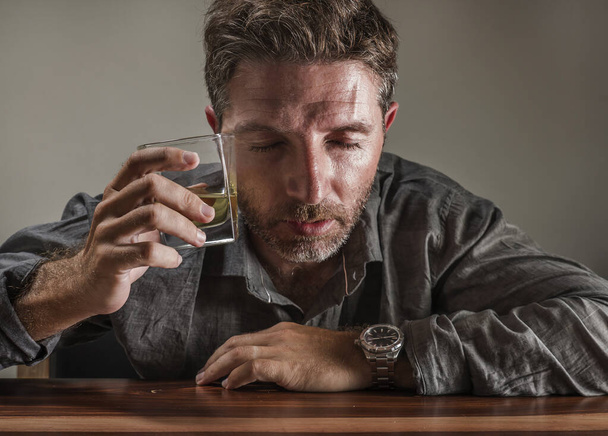Attractive alcoholic man . depressed addict isolated in front of whiskey glass drunk and wasted in dramatic expression suffering alcoholism and alcohol addiction - Photo, image