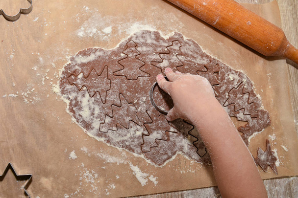 New Year`s Cookies. Cover, background, wallpaper. A rendered dough with baking molds. Cute baby little hand. u - Photo, Image