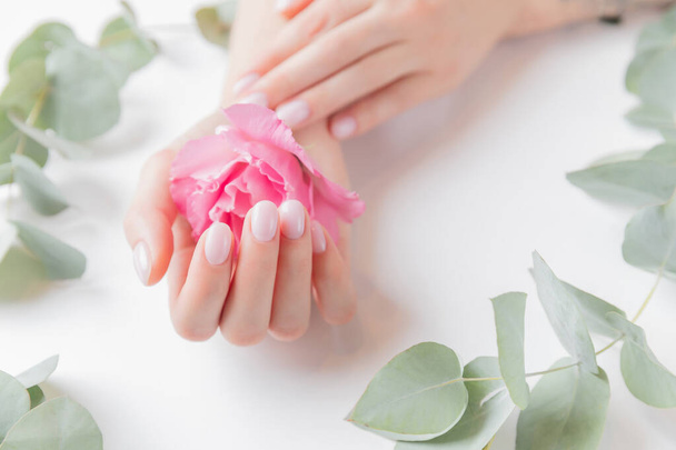 stilvolle einfache weibliche Hand Maniküre-Gel-Politur auf weißem Hintergrund mit Blume, Ansicht von oben. Konzept natürliche biologische Hautpflege - Foto, Bild