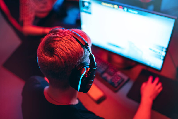 ヘッドフォン、赤と青の背景を持つプロのゲーマーは、オンラインゲームトーナメントPCコンピュータをプレイ - 写真・画像