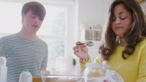 Young Downs Syndrome couple in kitchen at home measuring ingredients to bake cake together - shot in slow motion - Metraje, vídeo