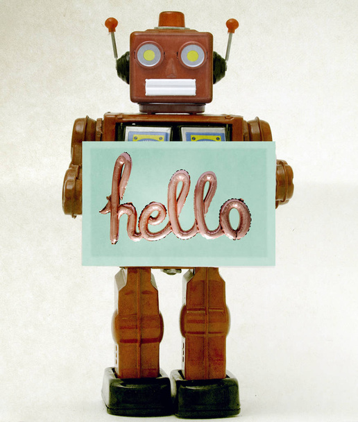 κόκκινο ρετρό ρομπότ που κρύβει μια πινακίδα καλωσορίσματος  - Φωτογραφία, εικόνα