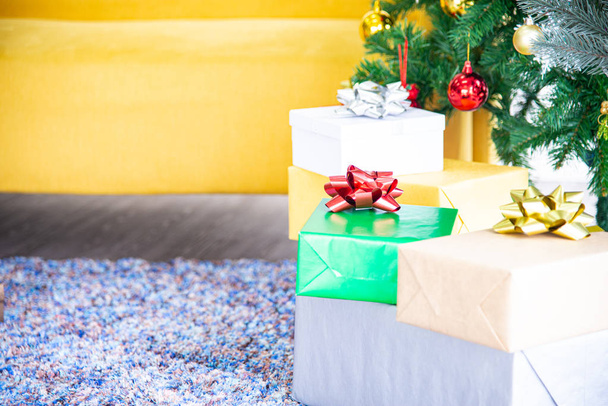 Conceito de Natal e Ano Novo. Closeup de Natal e Ano Novo caixas de presente coloridas com fita vermelha na decoração da árvore de Natal com fitas bolas e ornamentos de fundo
 - Foto, Imagem