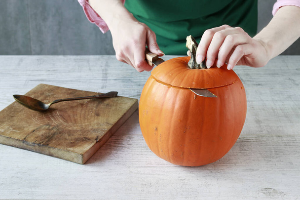 Woman shows how to transform a pumpkin into a halloween lantern - Foto, imagen