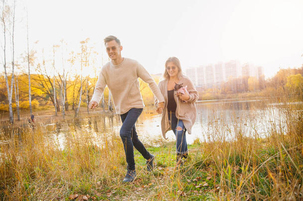 Szczęśliwa para w miłości biegnie przez jesienny las, człowiek uśmiech rzuca klon żółte liście - Zdjęcie, obraz