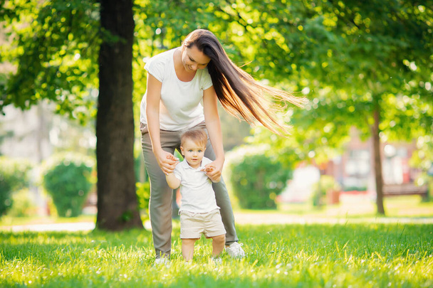 Caminar en el parque mamá e hijo, primer paso, aprender a ir niño. Concepto familia
 - Foto, imagen