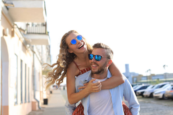 Beautiful young couple in love walking outdoors at the city street, hugging - Foto, imagen
