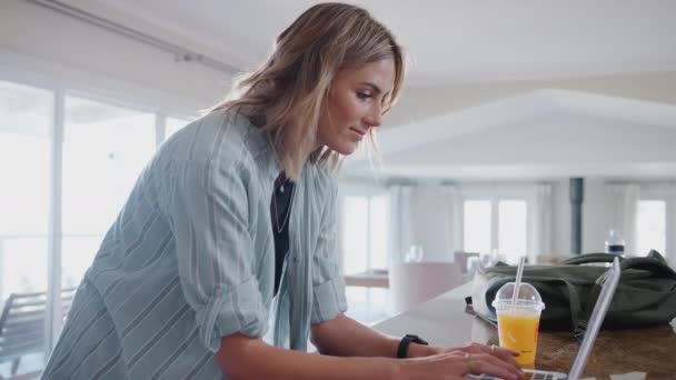 Casual geklede vrouw thuis downloaden van gezondheidsgegevens van smartwatch naar laptop - geschoten in slow motion - Video