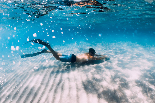 Freitaucher gleitet unter Wasser über sandigen Grund. Schwimmen mit Flosse - Foto, Bild