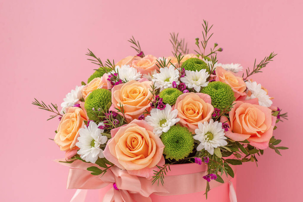Beautiful bouquet in a coral luxury present box with a pink bow, isolated on pink background - Valokuva, kuva