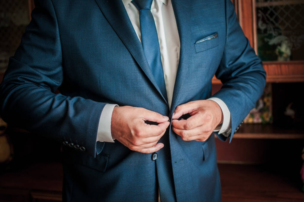 Bräutigam schnallt den Knopf an seiner Jacke an - Foto, Bild
