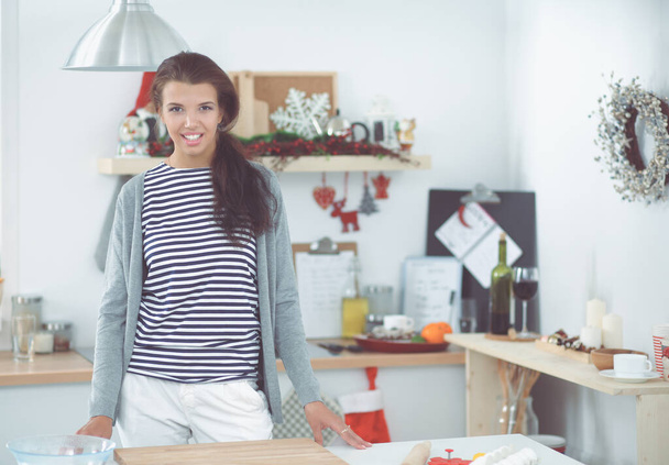 Smiling young woman standing in the kitchen - Φωτογραφία, εικόνα