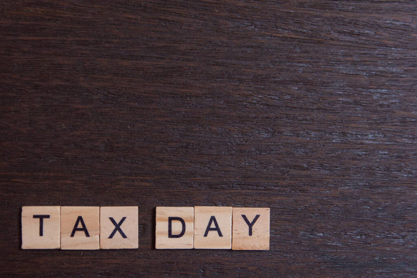 Daňový den s dřevěnými abecedními bloky na tmavém prkně dřevěné backgro - Fotografie, Obrázek