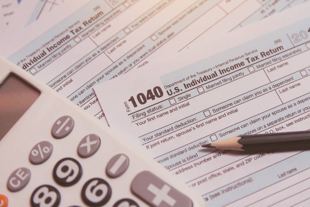 Temporada de impuestos. calculadora, lápiz sobre fondo de formulario de impuestos 1040
 - Foto, imagen