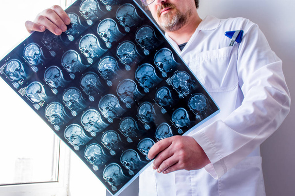 Doktor el ele tutuşan hastanın kafa, boyun ve beyin tomografisini inceliyor. Baş ağrısı gibi hastalıkların sebebini belirlemek için sinir sistemi organlarının enstrümantal teşhis anatomisinin konsept fotoğrafı. - Fotoğraf, Görsel