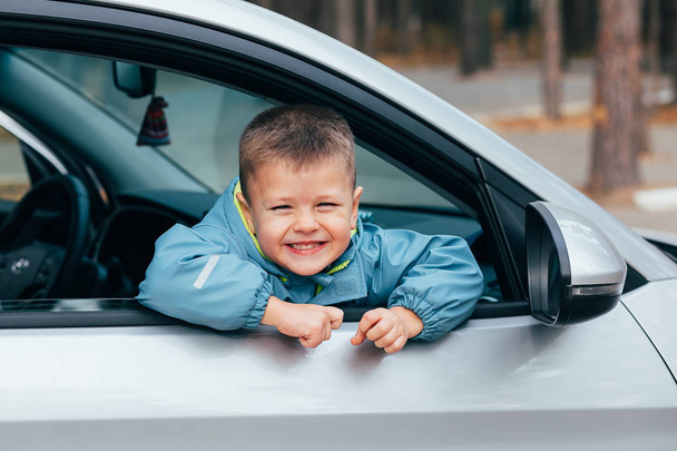 Lindo niño con una chaqueta azul viajando en el coche y mirando por la ventana y oliendo. Concepto de viaje
 - Foto, Imagen