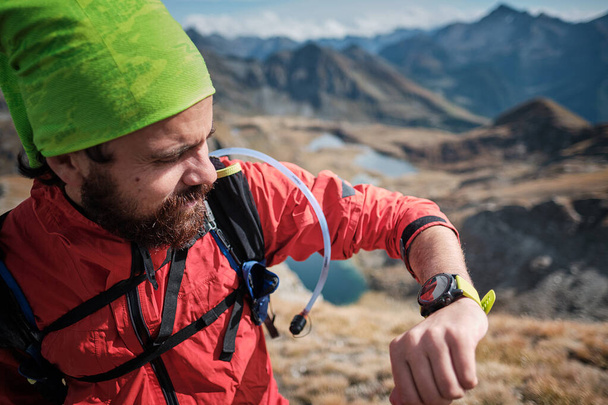 Νεαρός άνδρας κοιτάζοντας το GPS κομμάτι για wearable του, ενώ πεζοπορία στα βουνά σε μια σαφή ημέρα του φθινοπώρου - Φωτογραφία, εικόνα