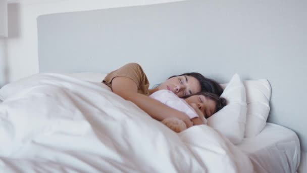 Mother and daughter sleeping peacefully in bed together as girl cuddles soft toy - shot in slow motion - Filmmaterial, Video