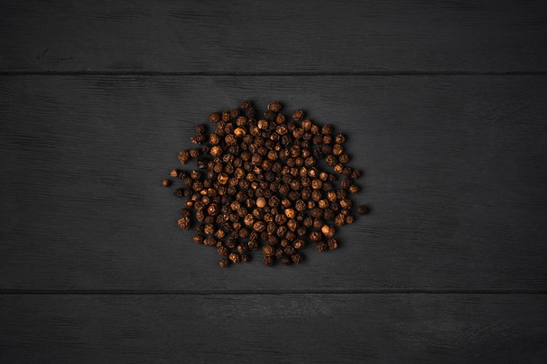 Black pepper peas on dark wooden background - Фото, изображение