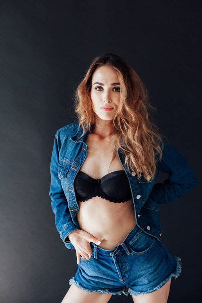 portrait of a woman in denim shorts and underwear on a black background - Foto, immagini