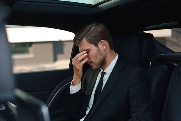 Tired overworked businessman dressed in full suit massaging nose while sitting in the car. - Φωτογραφία, εικόνα